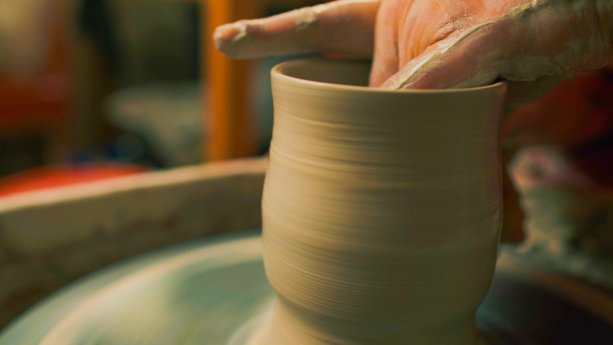 Hands shaping a spinning clay pot on a pottery wheel in Yelahanka.